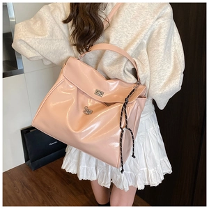 Detail of pink patent leather tote bag featuring a silver twist lock and woven rope accessory