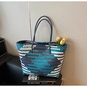 Detail of blue and white hand-woven tote bag with floral accents on a book background