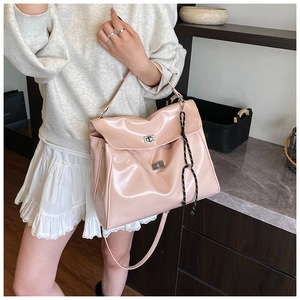 Detail of pink glossy patent leather bag with silver metal turn-lock and woven strap