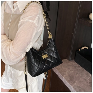 Détail du sac hobo matelassé noir avec fermoir doré et bandoulière chaîne sur modèle