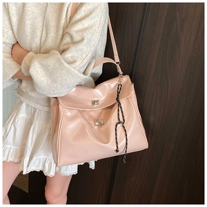 Detail of light pink patent leather handbag with silver twist lock and knot tassel
