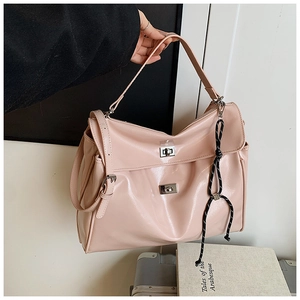 Close-up of pink glossy faux leather tote bag with silver twist locks and woven charm