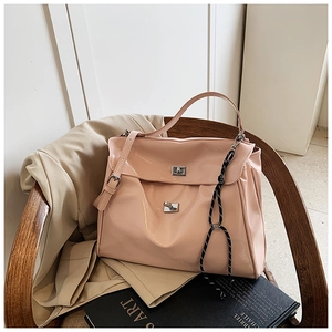 Detail of light pink patent leather tote bag with metallic twist locks on wooden chair