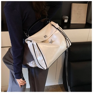 Close-up of white glossy leather tote bag with a metal twist lock and woven strap detail