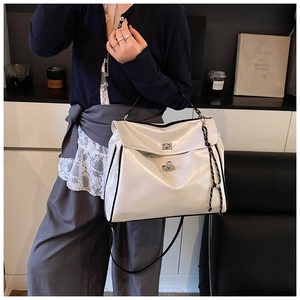 Detailed macro view of the glossy cream tote bag featuring a silver metal twist lock