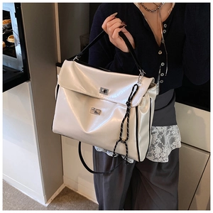 Close-up of creamy white glossy tote bag featuring mixed color woven strap and metal buckle