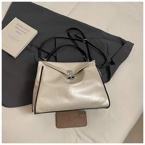 Top view of cream faux leather handbag with silver lock and black contrast handle