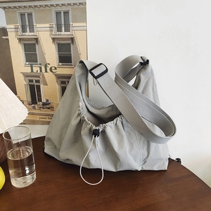 Minimalist light gray nylon drawstring tote bag with adjustable wide shoulder strap