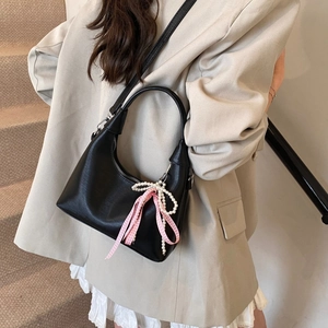 Détail du sac demi-lune noir mat avec breloque en perles et nœud à carreaux