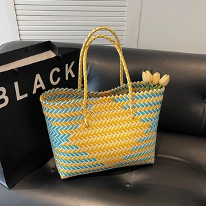 Large hand-woven tote bag in yellow and blue herringbone knit on a sofa