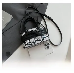 Detail of mini black and white snakeskin pattern bag with leather trim and crossbody strap