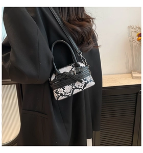 Chic snakeskin pattern crossbody bag styled on a black blazer with dual top handles