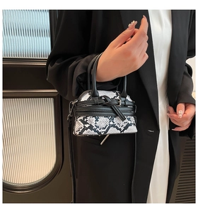 Detail of snake skin pattern faux leather mini bag with knot strap and metal buckle
