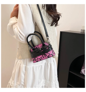 Side view of pink snakeskin pattern mini bag worn by a model in a beige interior