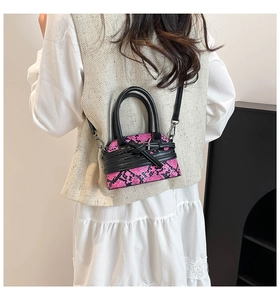 Rear view of a model wearing a mini snakeskin handbag with pink and black patterns