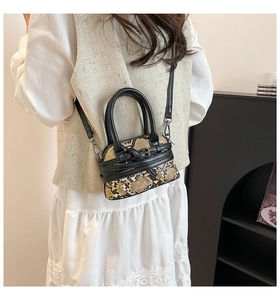 Close-up of snakeskin pattern crossbody bag with metal buckle and adjustable strap