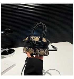 Detailed macro view of snakeskin pattern handbag with black leather trim and metal buckle