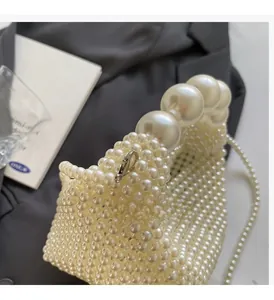 Detail of handmade pearl handbag featuring large pearl handle and metallic lobster clasp