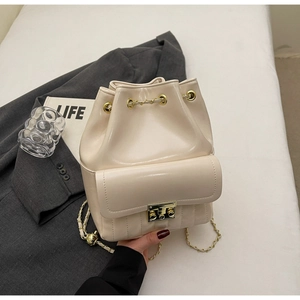 Detail of cream white bucket bag with gold hardware and chain strap on stylish setting