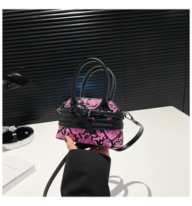 Detailed shot of mini shell bag featuring pink and black snakeskin pattern and handle
