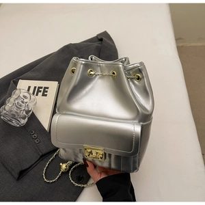 Detail of silver metallic bucket bag featuring gold chain and turn-lock closure
