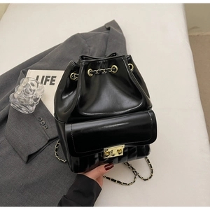 Detail of black glossy leather bucket backpack with gold chain and quilted bottom