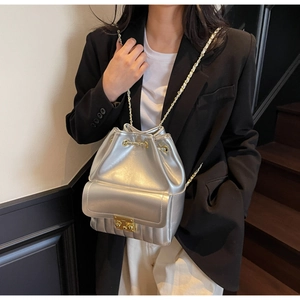 Close-up of shiny silver metallic bucket bag with gold chain strap and quilted base