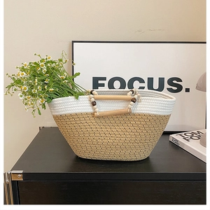 Detail of woven bicolor tote bag featuring smooth wooden handles and decorative beads
