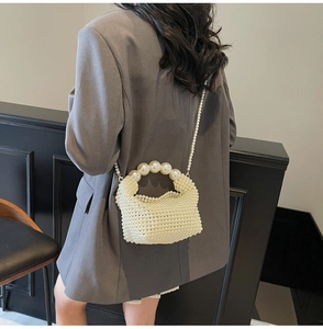 Detail of handmade pearl woven handbag showing arch handle and long crossbody chain