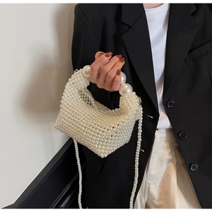 Detailed view of handmade pearl handbag featuring intricate beaded weave and long strap