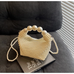 Detail showing handcrafted pearl weaving texture and large beaded top handle on the evening bag