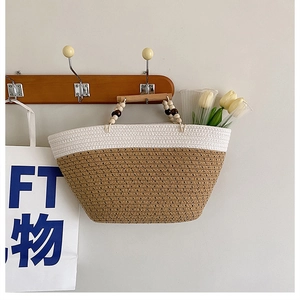 Detail of woven tote bag featuring bicolor straw texture and decorative wooden bead handles
