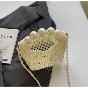 Detail of handmade pearl handbag with large decorative pearls on grey blazer background