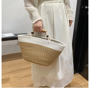 Detail of woven tote bag featuring bicolor stitching and wooden beaded handles