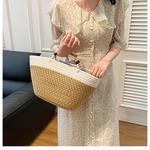Detail of woven tote bag featuring white and khaki contrast with wooden beaded handle
