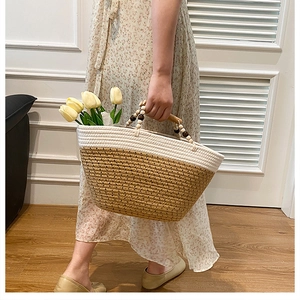 Detail of hand-woven tote bag with wooden handles and floral decorative accents
