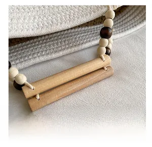 Detail of woven tote bag with smooth wooden handles and decorative bead accents