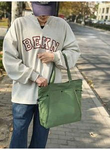 Outdoor-Detail einer grünen Nylon-Tasche mit funktionalen Kordelzug-Seitenschnallen