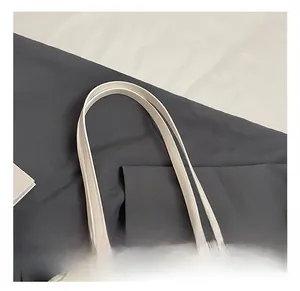 Detailed view of white leather bucket bag with elegant pearl charm and dual long handles