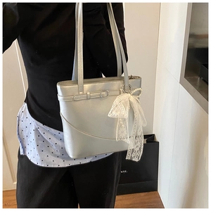 Detail of silver tote bag with white lace bow and pearl charm on thin straps