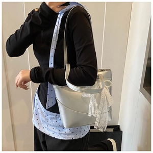 Detail of silver bucket bag with white lace bow and pearl charm accessories