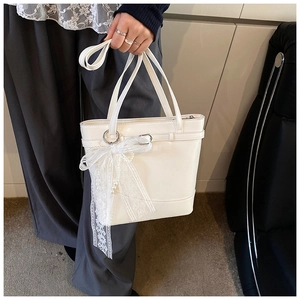 Detail of white PU bucket bag featuring a large lace bow with delicate pearl accents