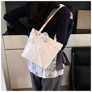 Detail of white glossy leather tote bag with large lace bow and pearl embellishment