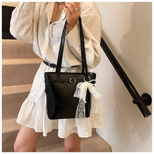 Detail of black matte PU leather tote bag with white lace bow and pearl charm ornament