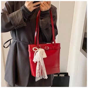 Detail of red patent leather bucket bag with white lace bow and pearl charm