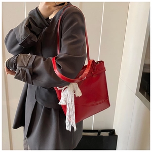 Detail of red leather bucket bag with lace bow and elegant pearl chain shoulder strap