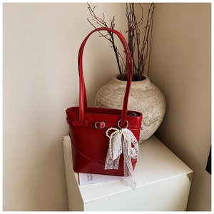 Detailed macro view of a red leather bucket bag with a lace pearl bow and silver buckle