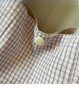 Close-up of soft plaid fabric texture with round button closure on minimalist tote bag
