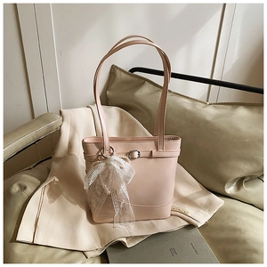 Detail of pink faux leather tote bag with elegant lace bow and pearl bead charm