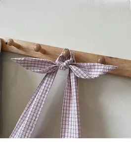 Detail of pink and brown checkered fabric shoulder strap tied in a stylish bow knot